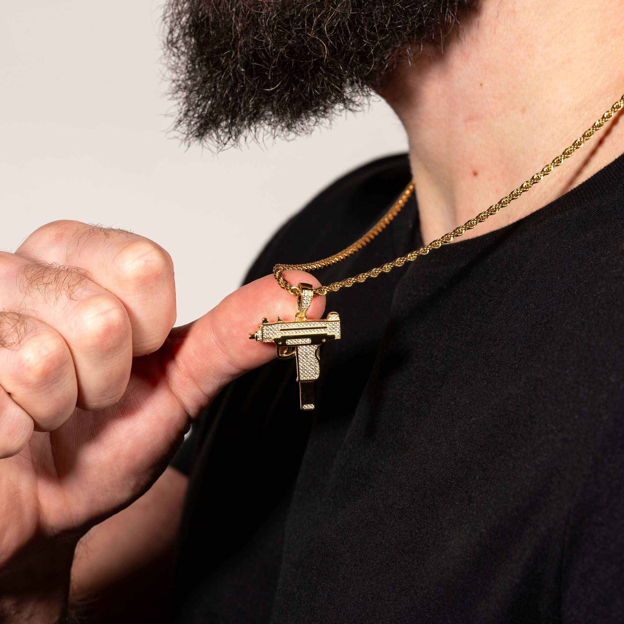 Uzi Pendant made of 925 sterling silver with clear CZ stones, held by a person wearing a chain.