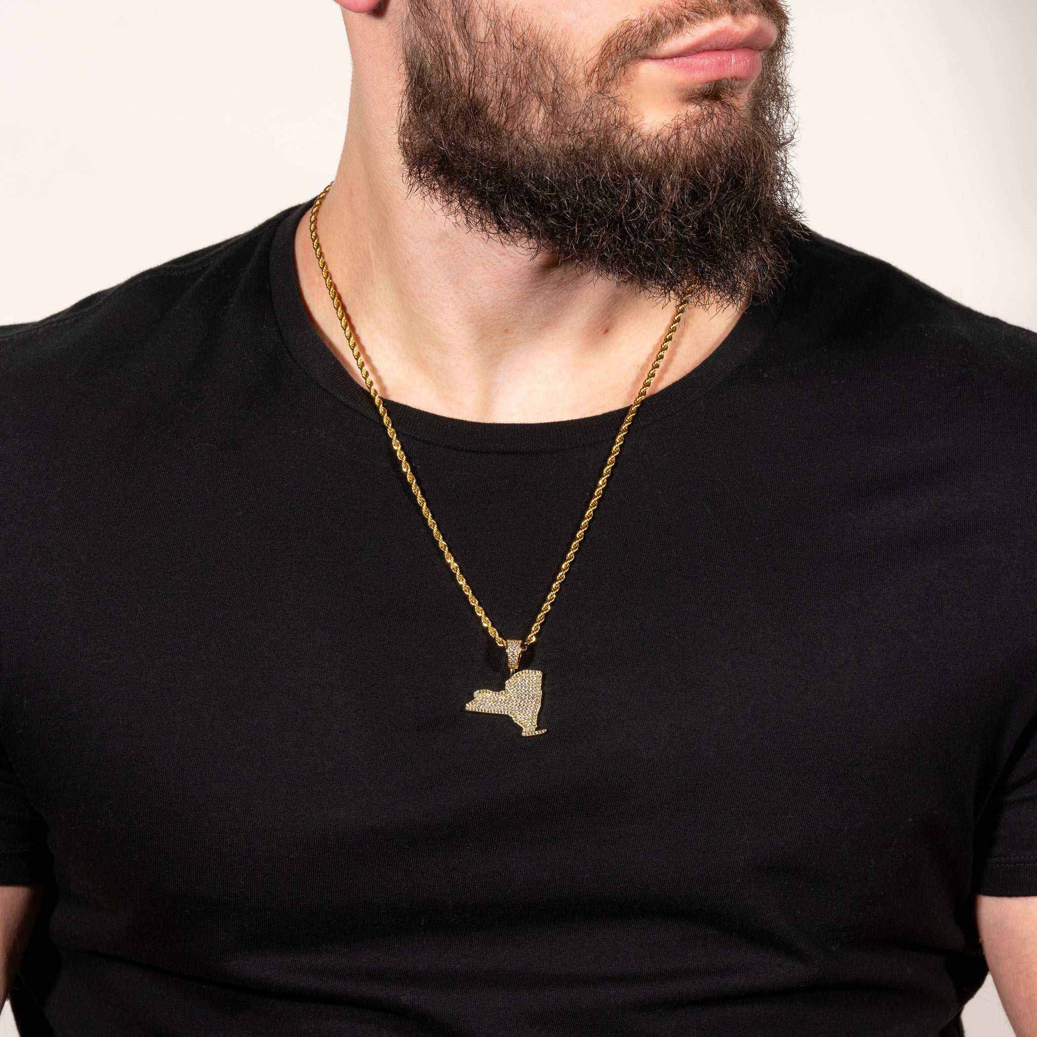 Man wearing gold New York pendant necklace on a black shirt.