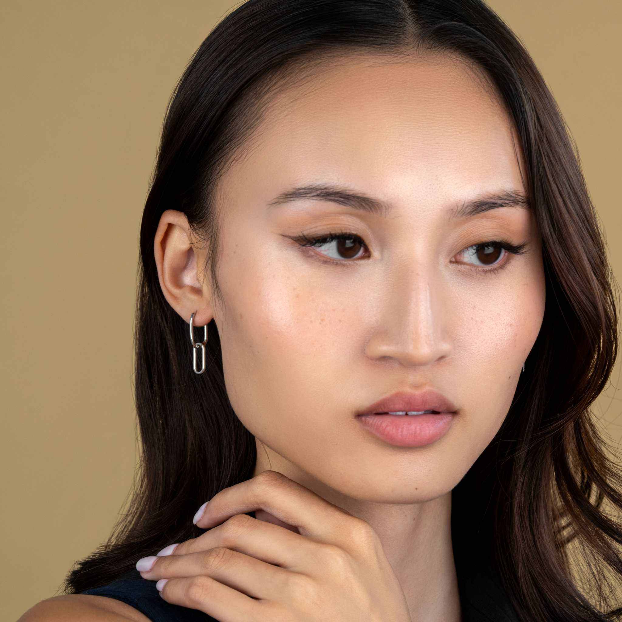Link earrings with delicate chain design in sterling silver and brass, featuring rhodium and 18K gold finish, worn by a model.