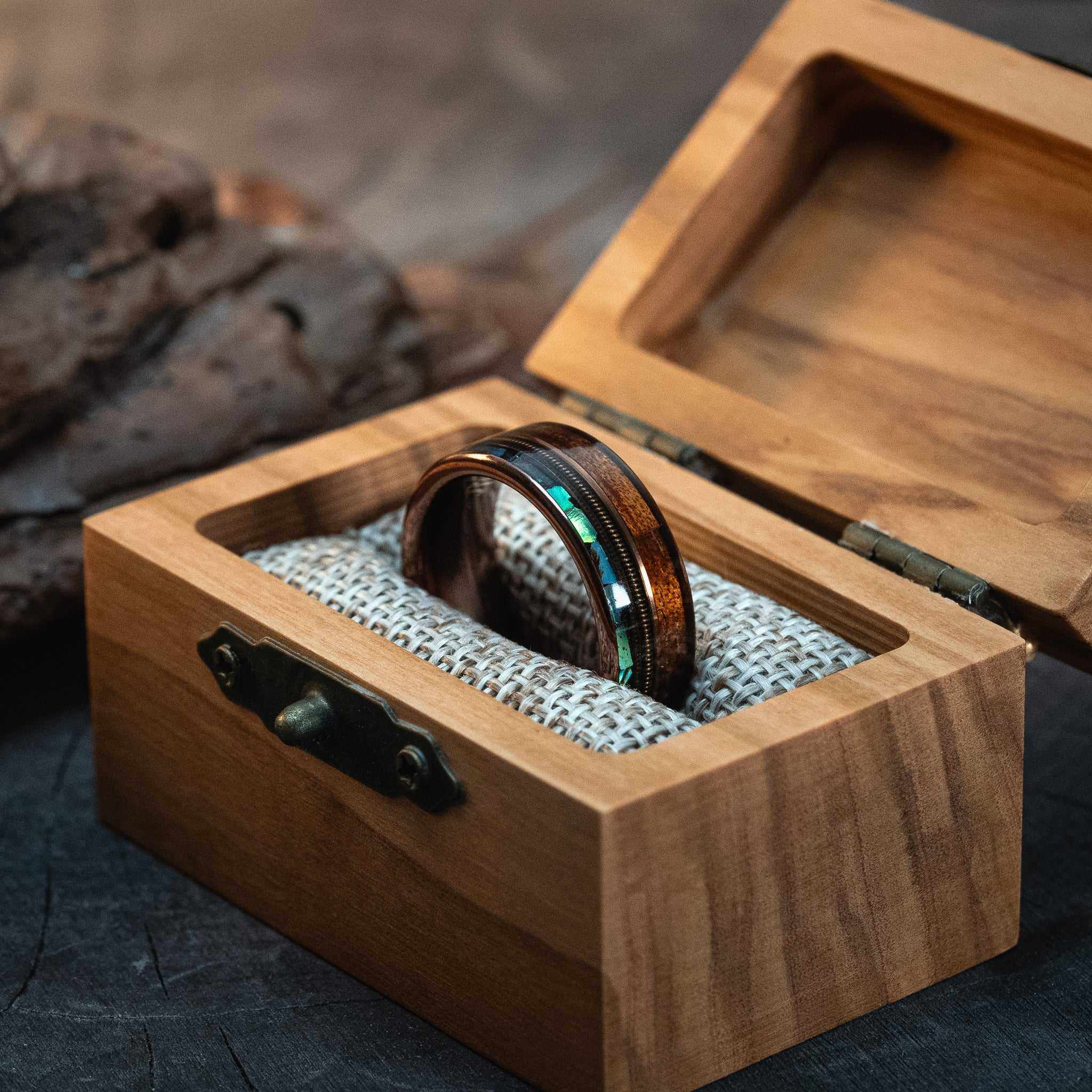 Rose gold tungsten ring with guitar string, abalone shell, and Hawaiian Koa wood inlay in olive wood box.
