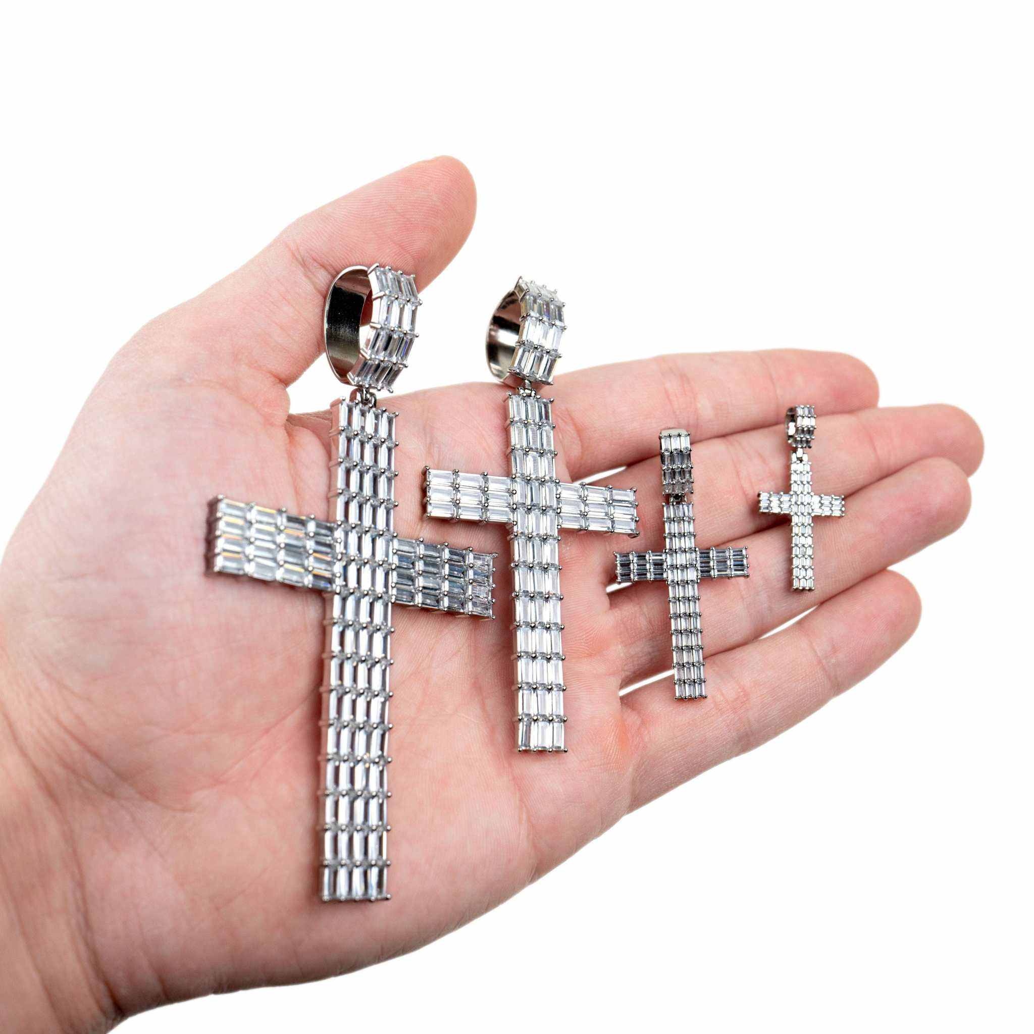 Baguette Silver Cross Pendant in multiple sizes held in hand.
