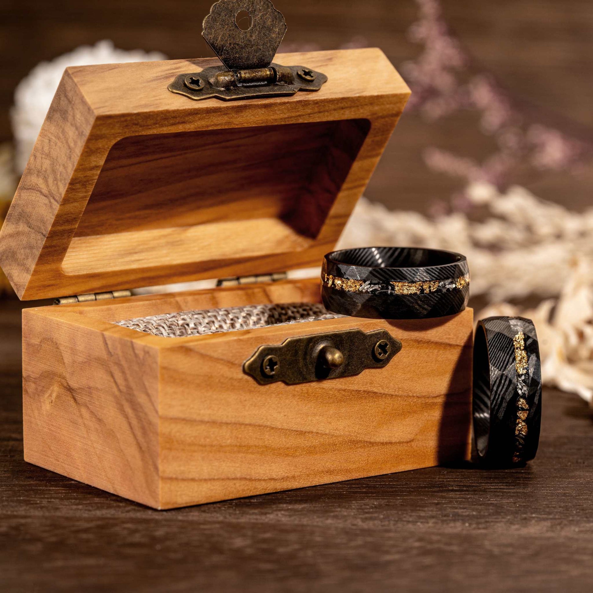 Damascus Meteorite & Crushed Gold Ring in olive wood box on dark surface, showcasing black steel hammered band and unique design.