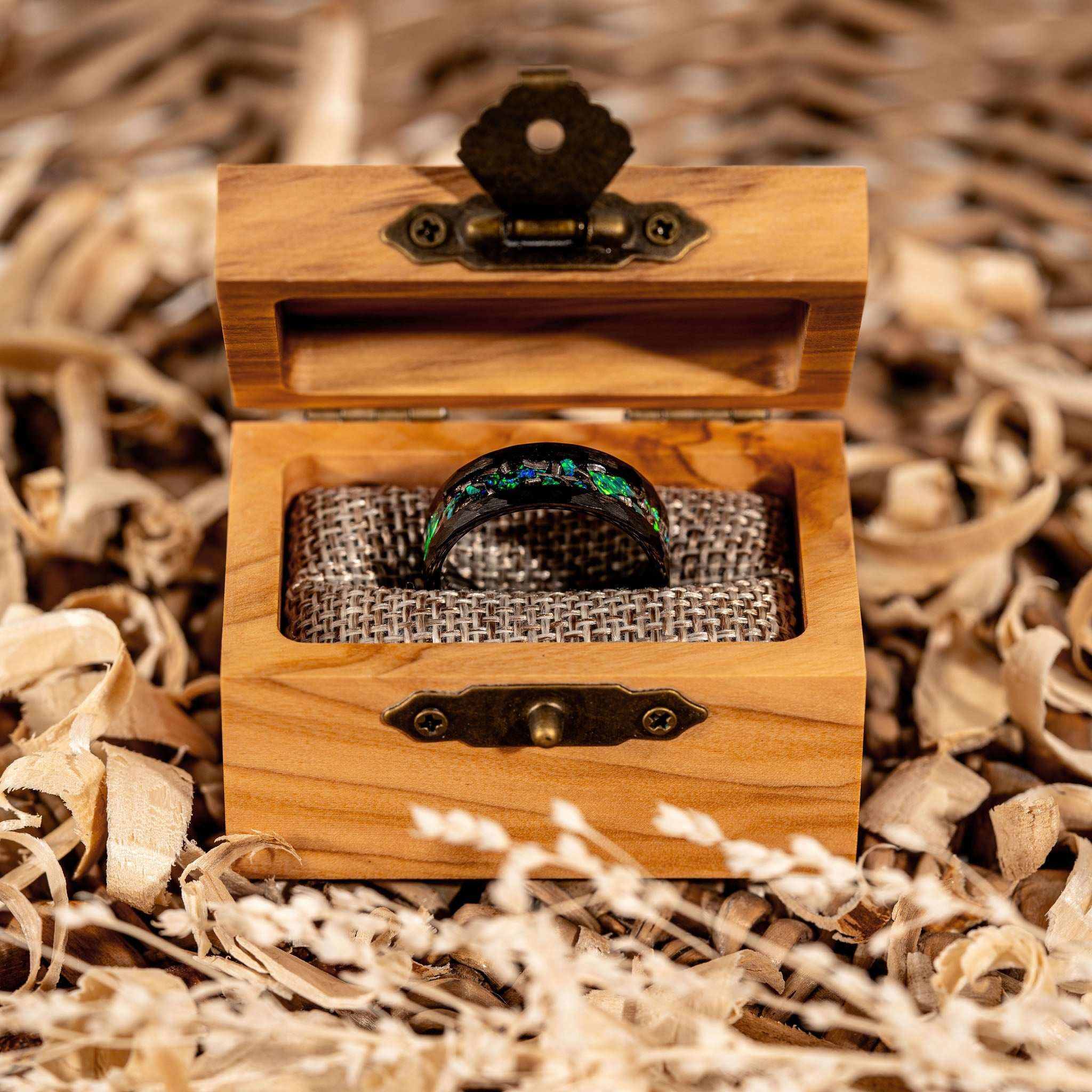 Meteorite and green opal ring in a wooden box surrounded by natural shavings.