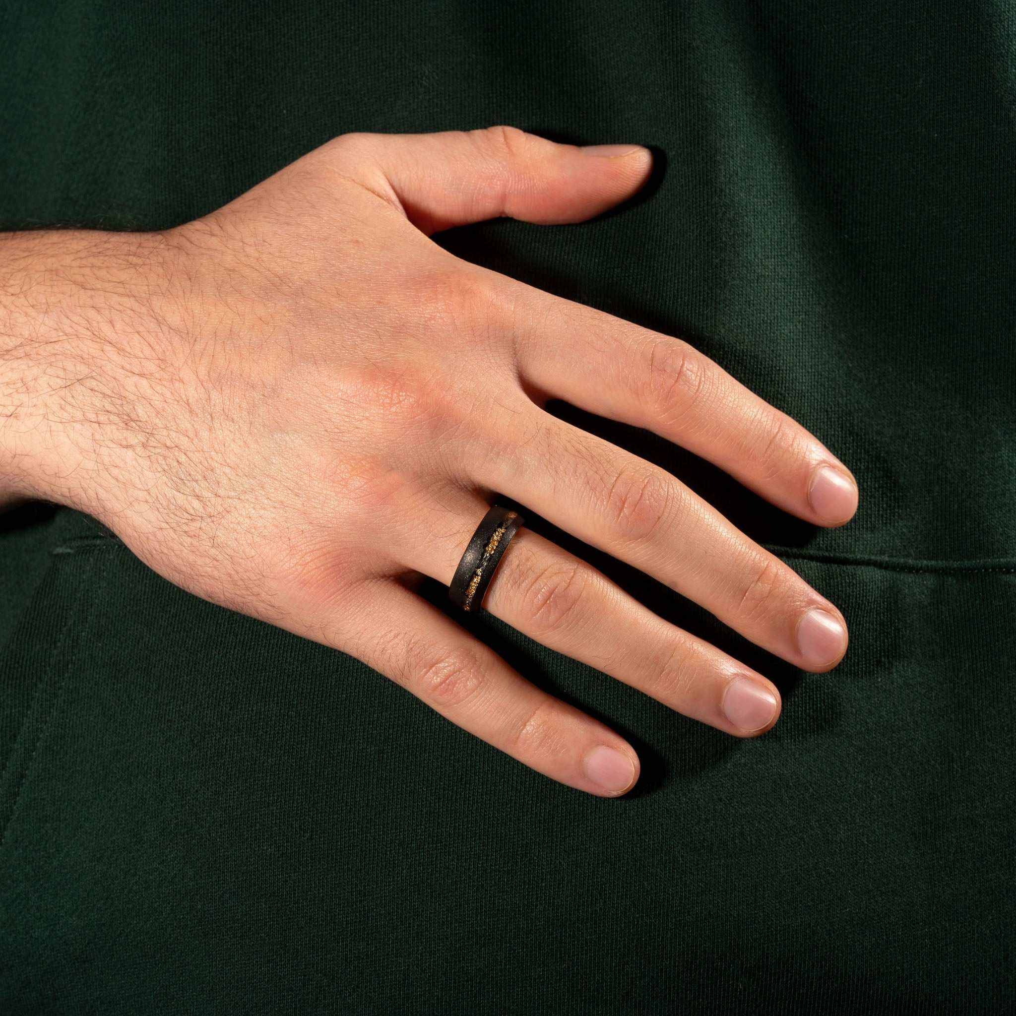 Sandblasted gold leaf meteorite ring on hand, displaying unique design and superior craftsmanship.