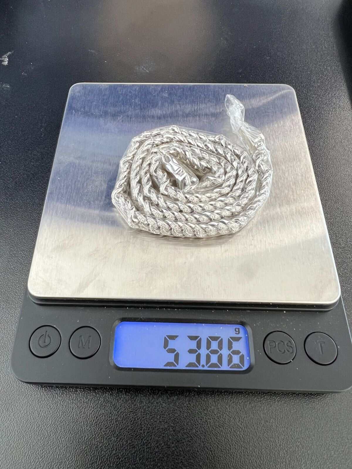 Men's moissanite Cuban curb link chain in silver, weighing 53.86g on digital scale.