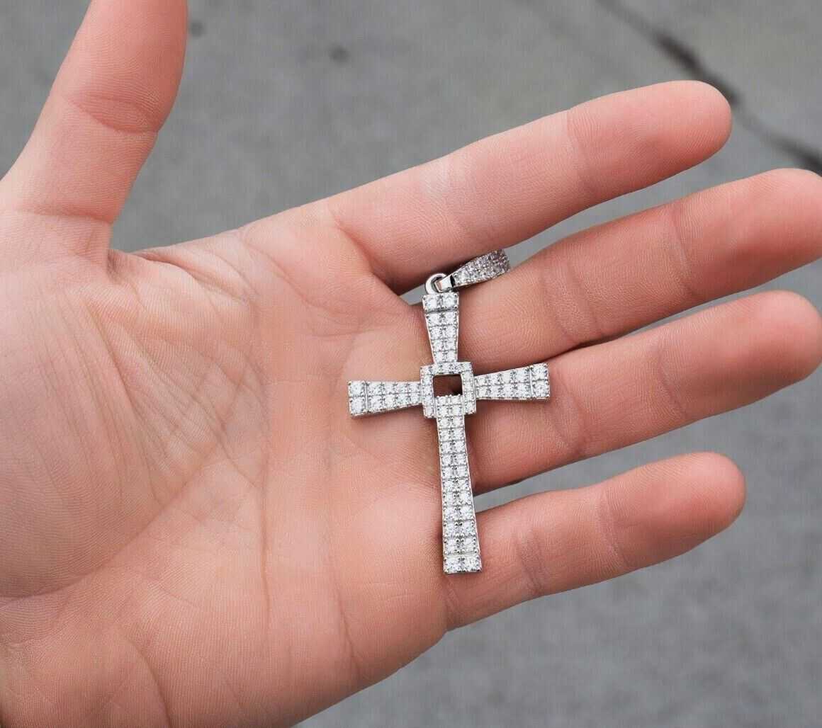 Silver cross pendant with CZ stones in 925 sterling silver held in a hand.