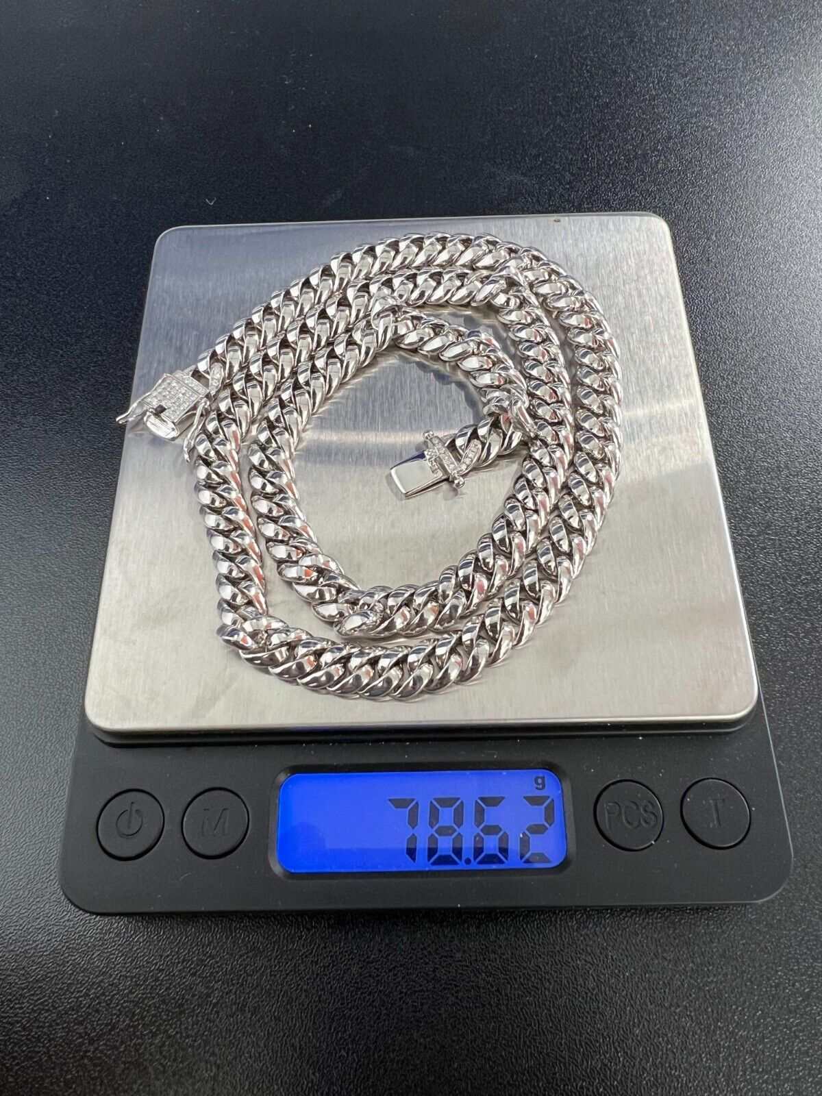 Mens solid 925 sterling silver Cuban link chain with moissanite stones on a scale.
