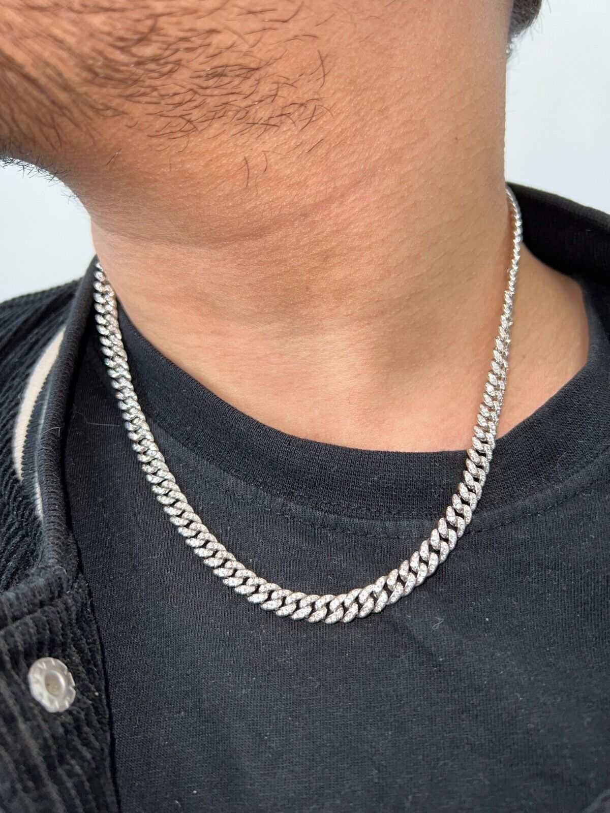 Mens real moissanite iced Cuban link chain in sterling silver worn on neck.