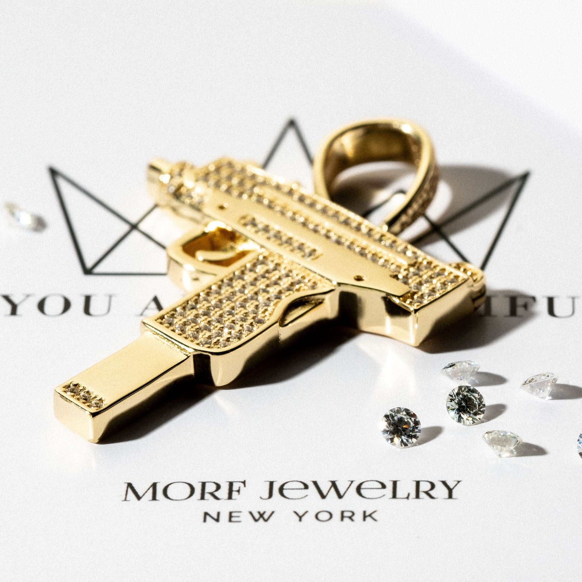 Uzi Pendant in 14k yellow gold-plated with handset clear cz stones on a jewelry display.