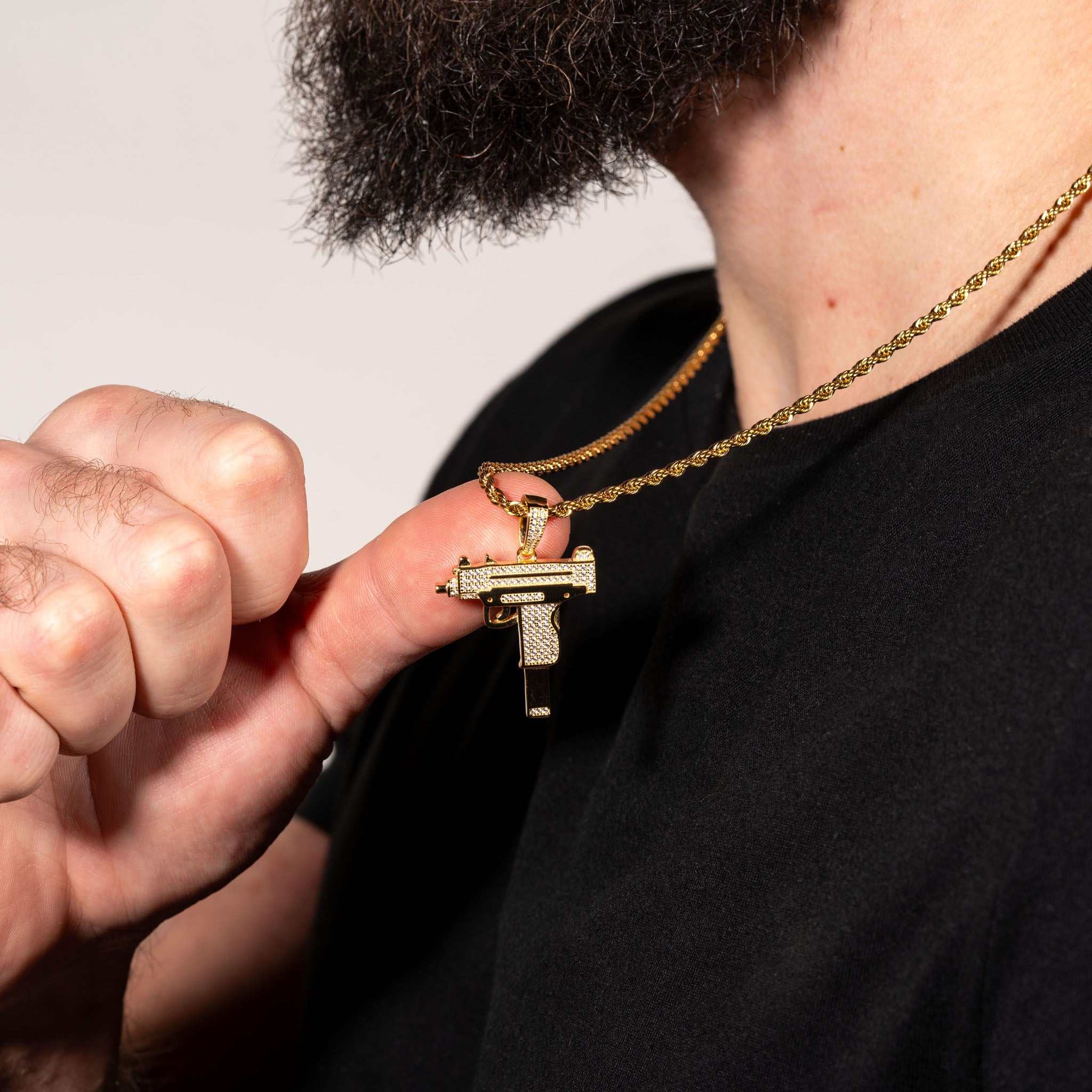 Uzi Pendant made of 925 sterling silver with clear CZ stones, held by a person wearing a chain.