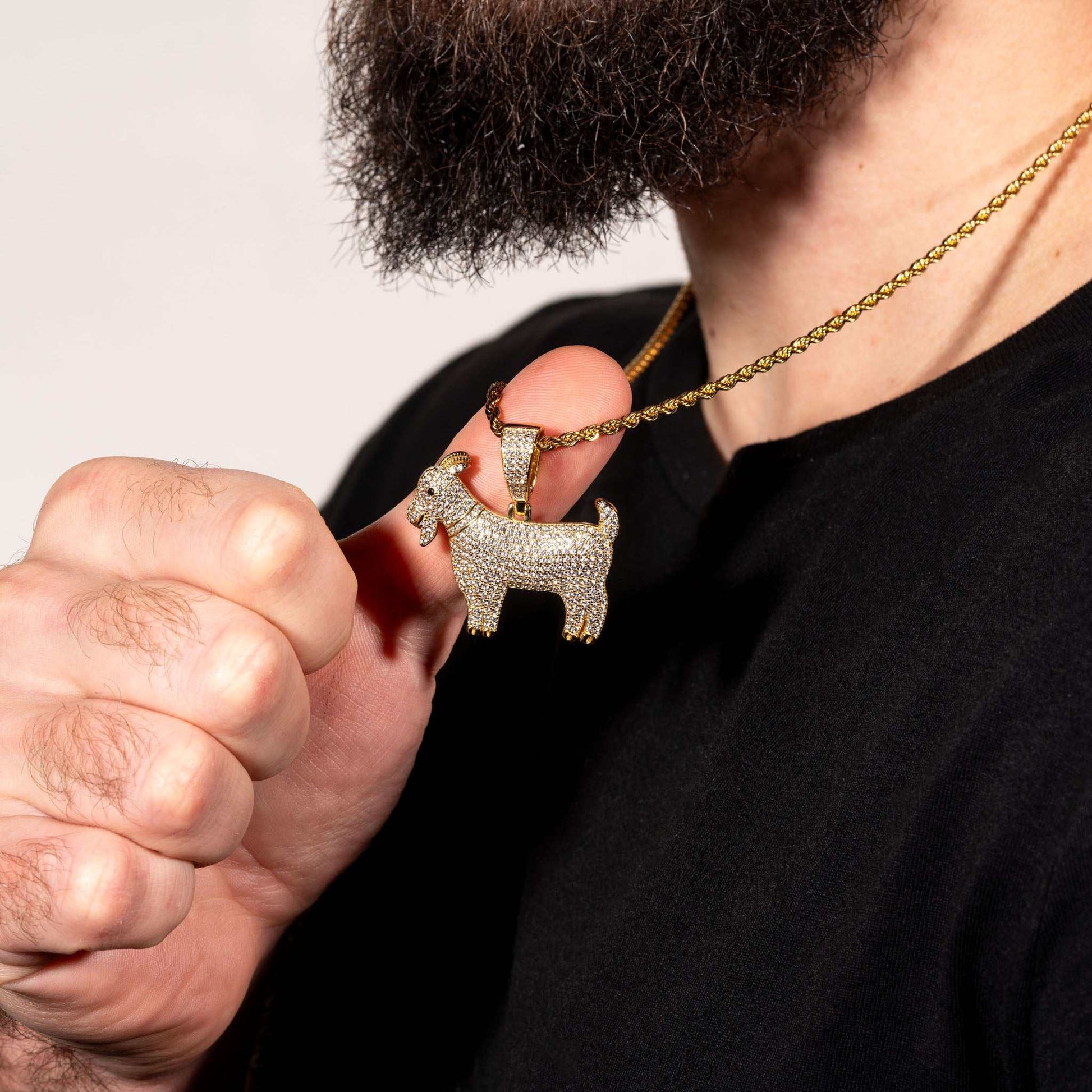 GOAT pendant in sterling silver with gold plating held by a person, showcasing detailed craftsmanship.