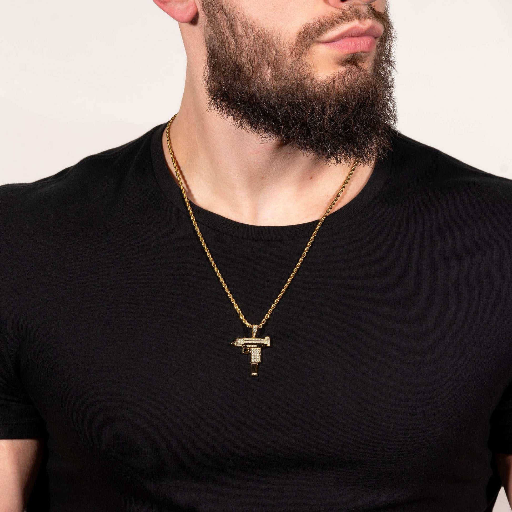 Man wearing Uzi Pendant on a chain, featuring rhodium or 14k yellow gold-plating with clear cz stones, crafted in pure 925 silver.