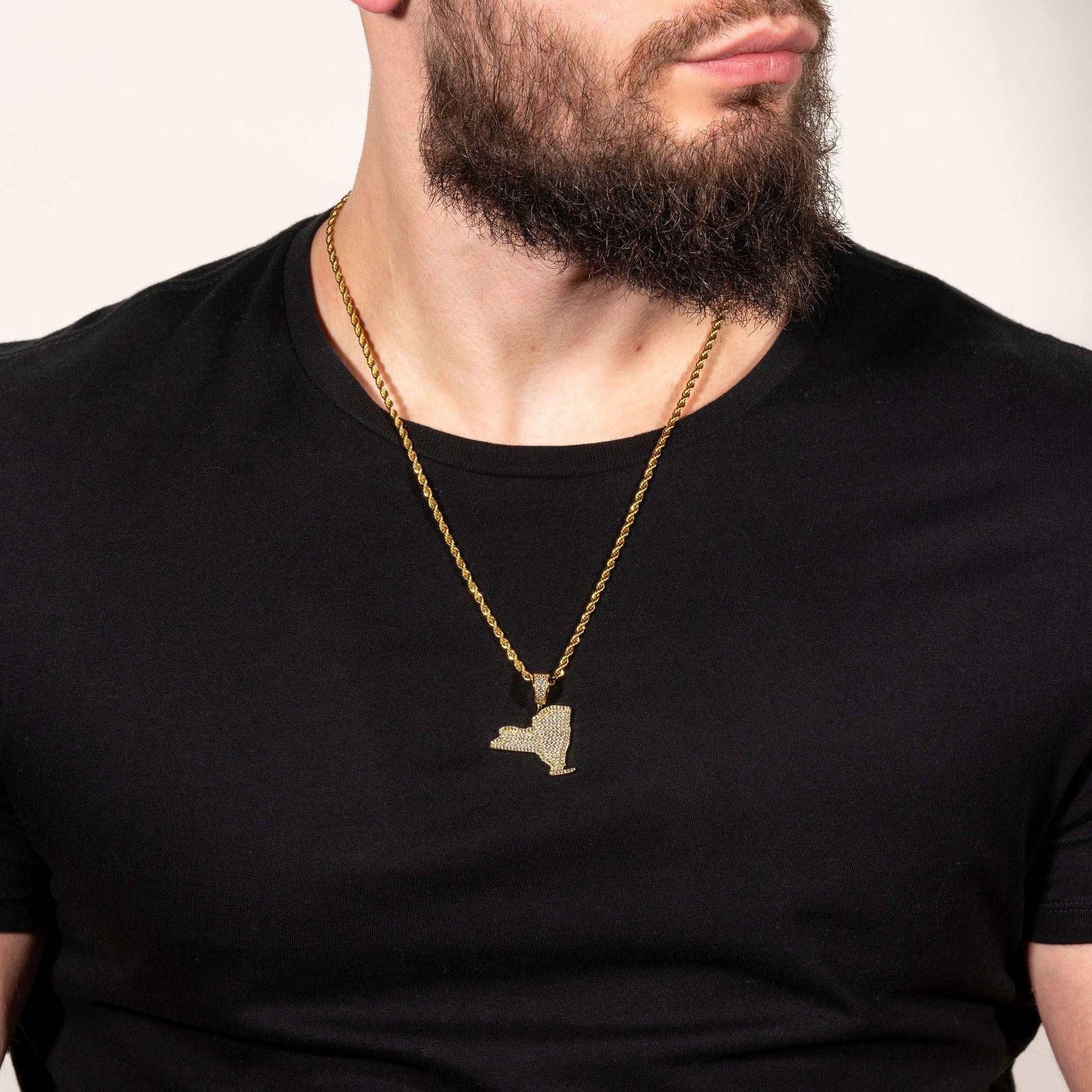 Man wearing gold New York pendant necklace on a black shirt.
