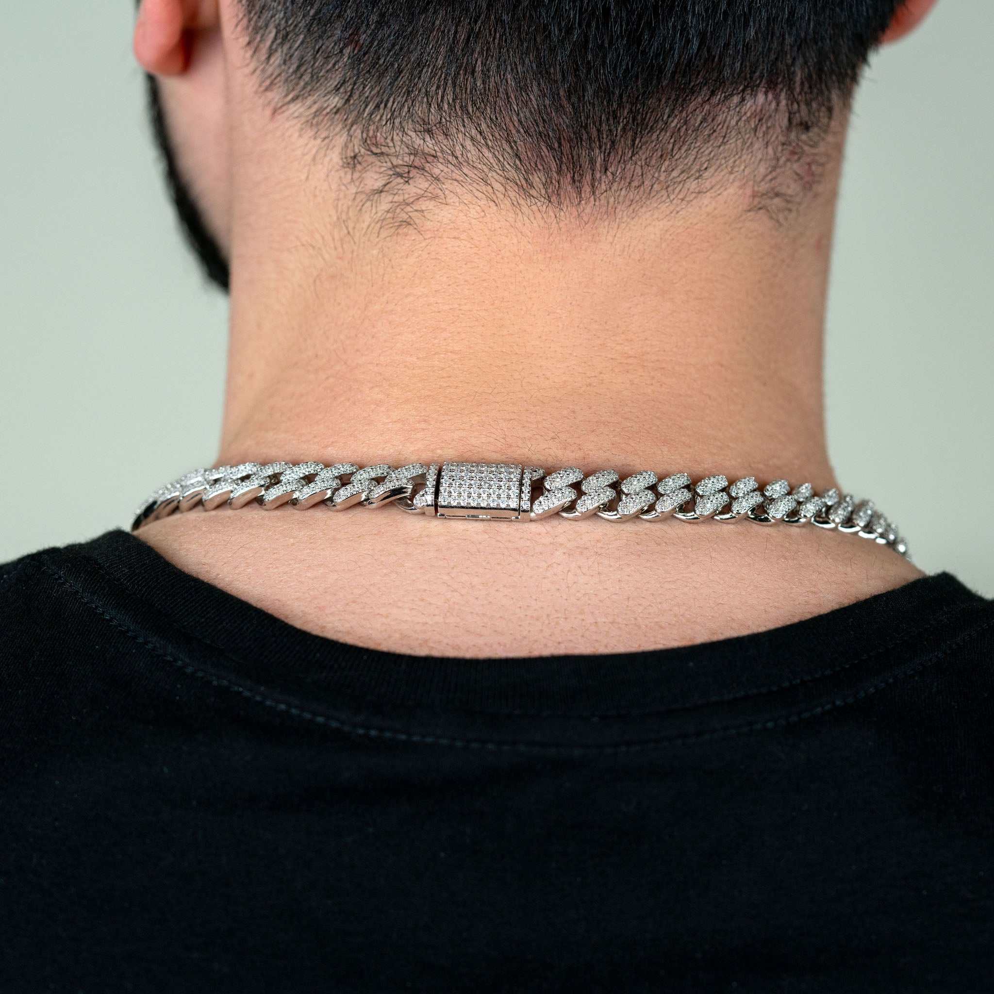12mm Moissanite Miami Cuban Link Chain in sterling silver worn by a person.