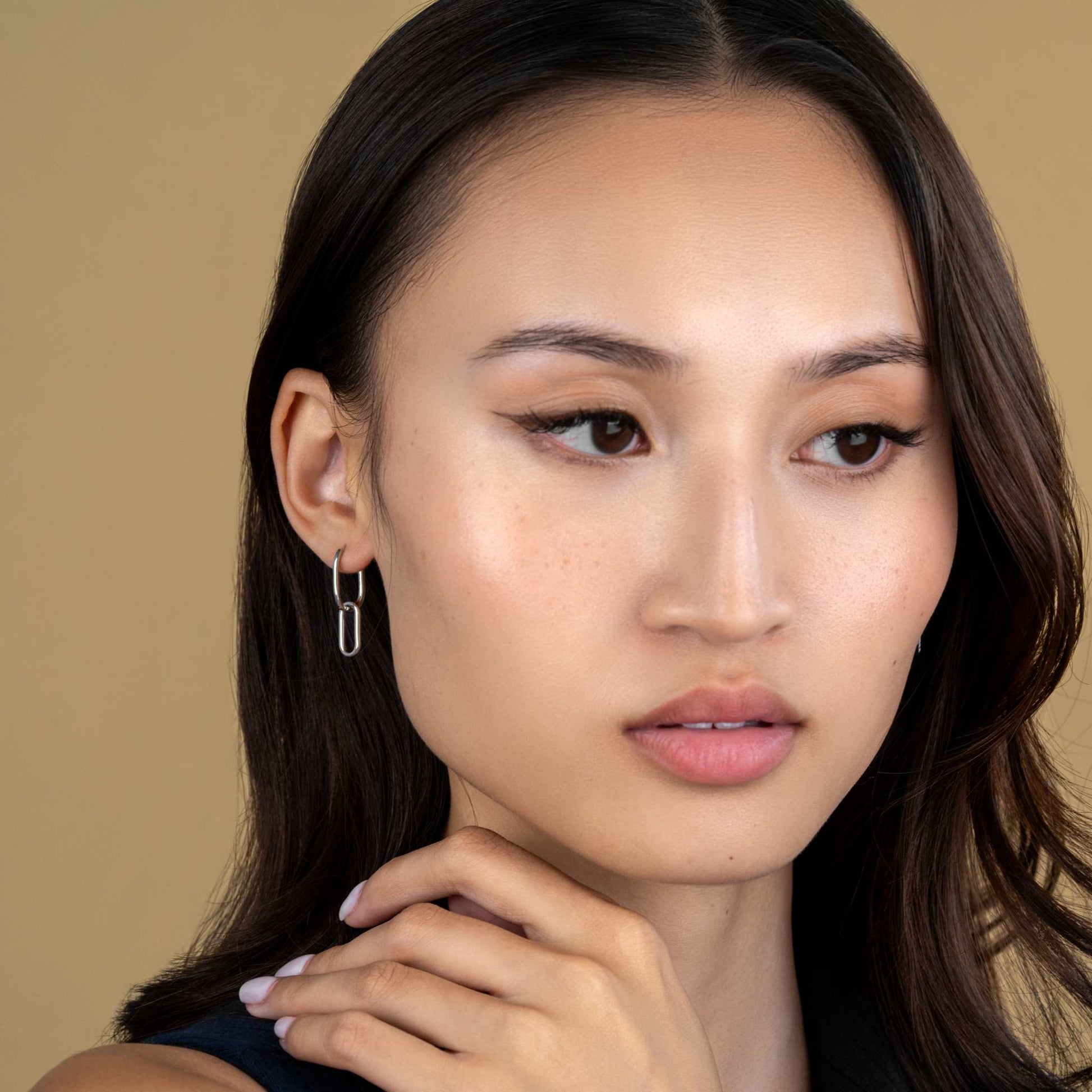 Link earrings with delicate chain design in sterling silver and brass, featuring rhodium and 18K gold finish, worn by a model.