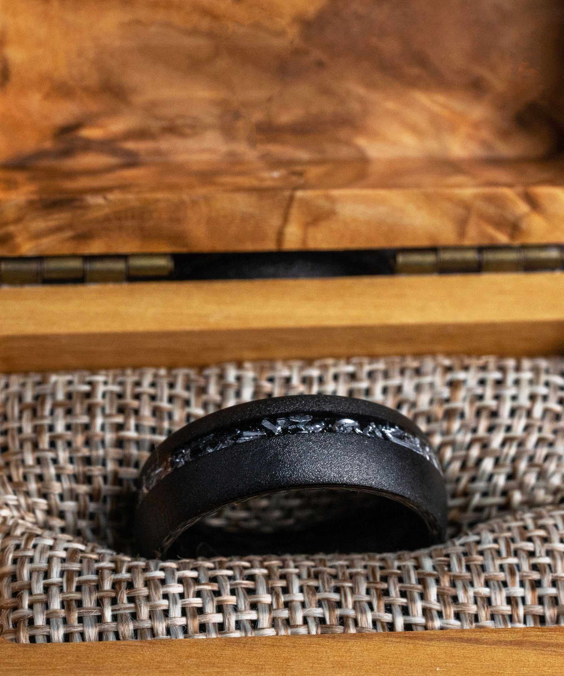 Unique meteorite black ring crafted from Muonionalusta meteorite, displayed in an elegant wood box.