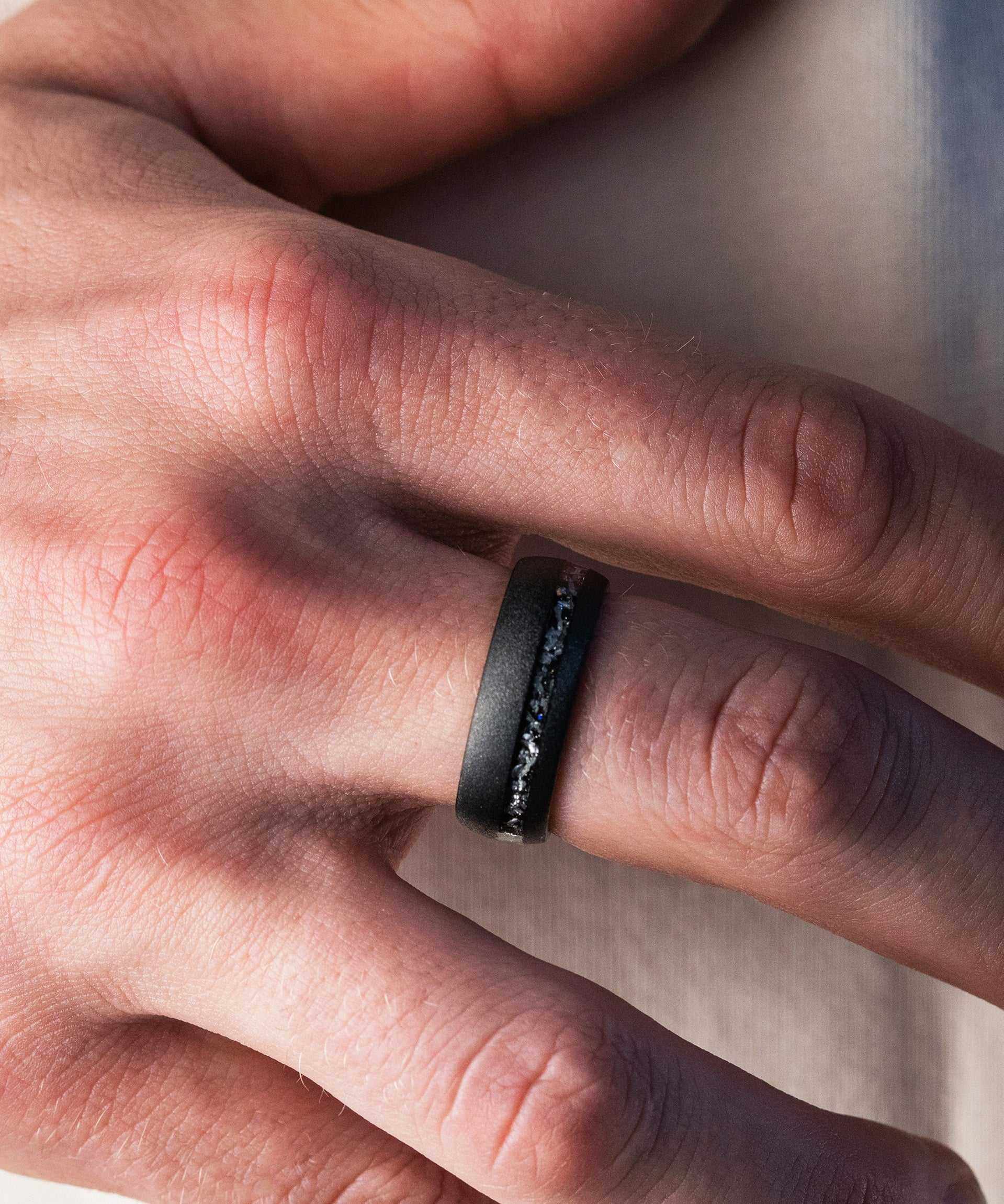 Hand wearing a unique meteorite black ring made from Muonionalusta meteorite.