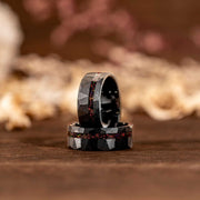 Black tungsten opal ring with hammered texture and iridescent inlay on a wooden surface