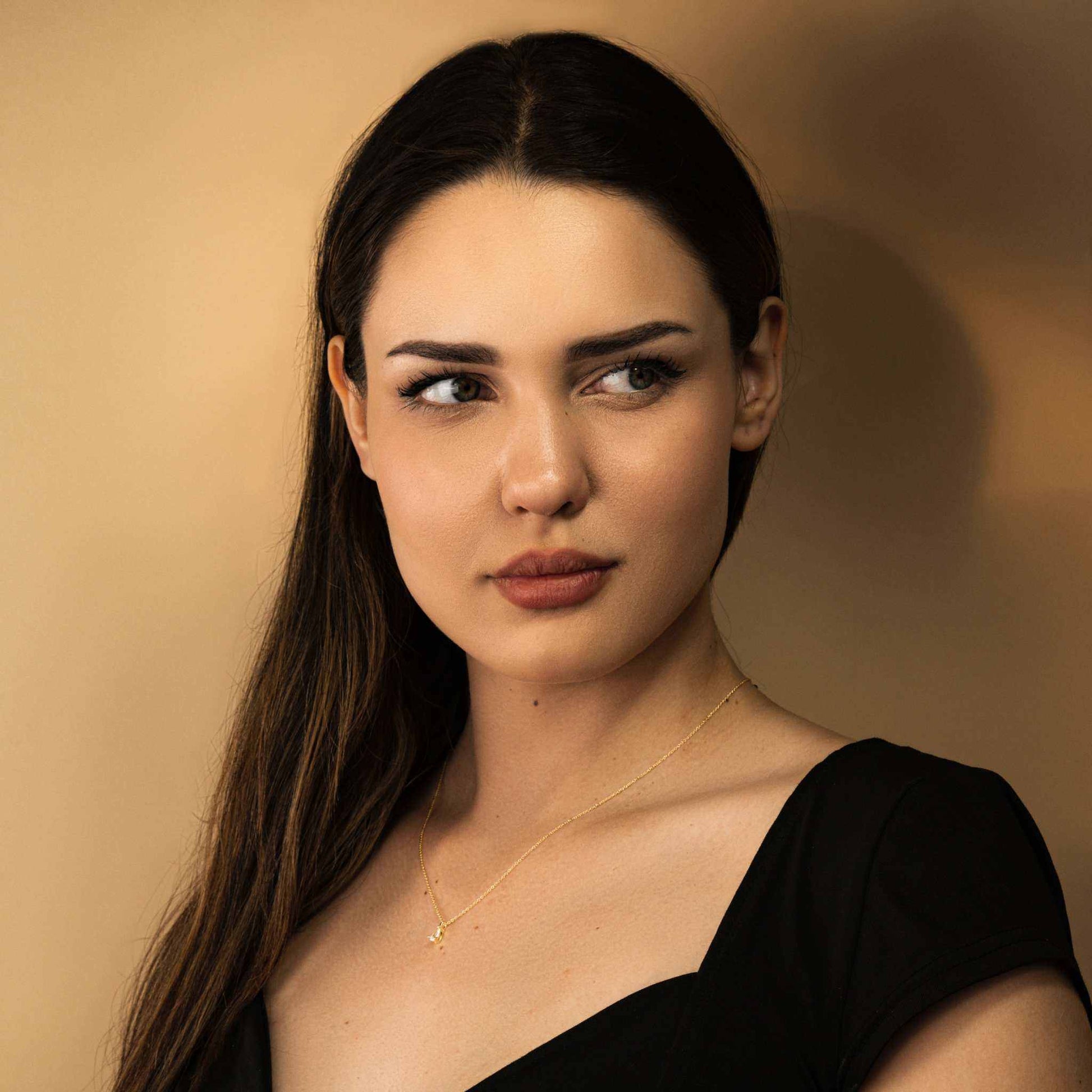 Elegant woman wearing the Delight Teardrop Necklace by Morf Jewelry, featuring a pear-shaped diamond on a gold-finished sterling silver chain.