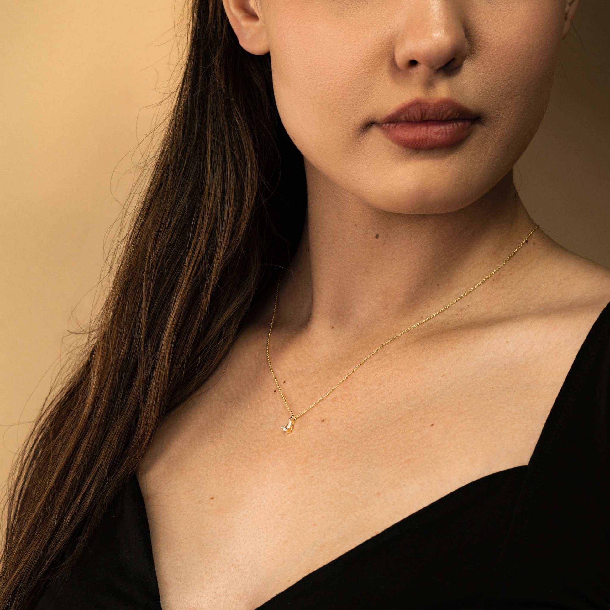 Teardrop diamond necklace on woman wearing black top.