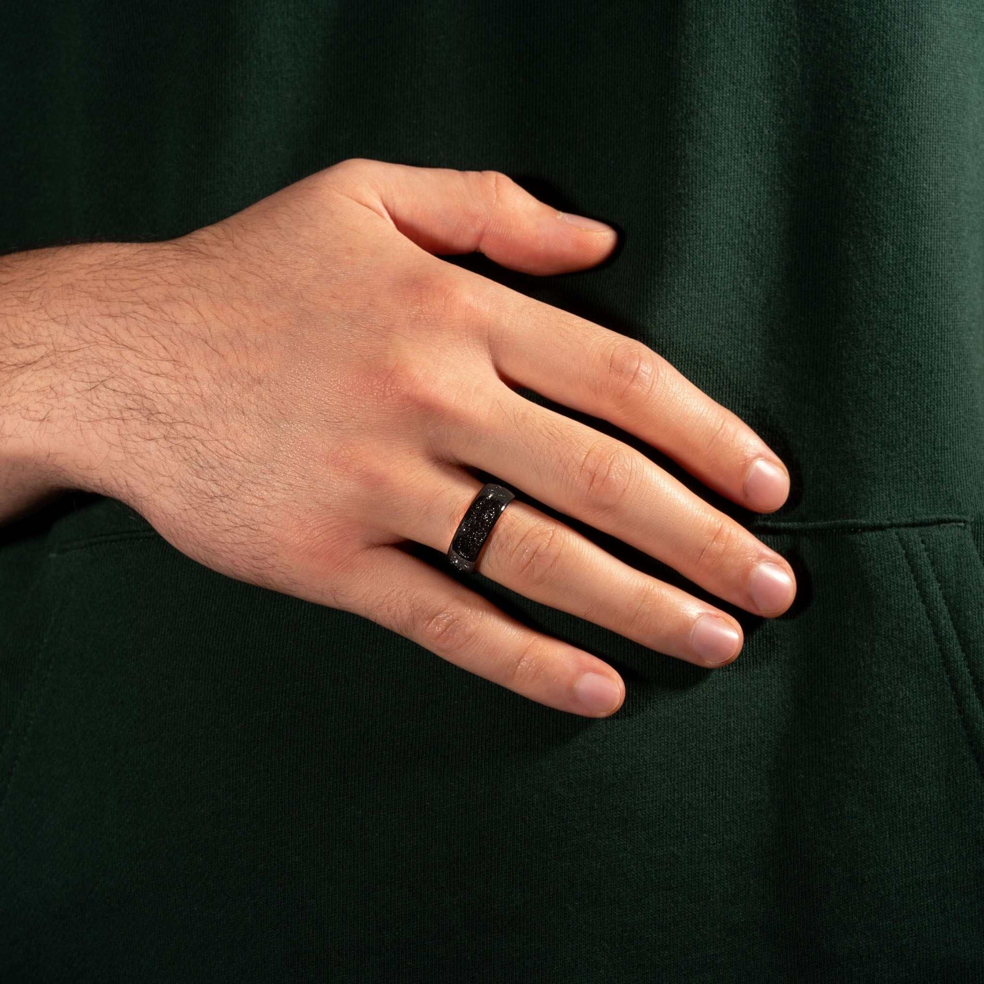 Eclipse Galaxy Ring, black tungsten band with meteorite iron, shown on hand.