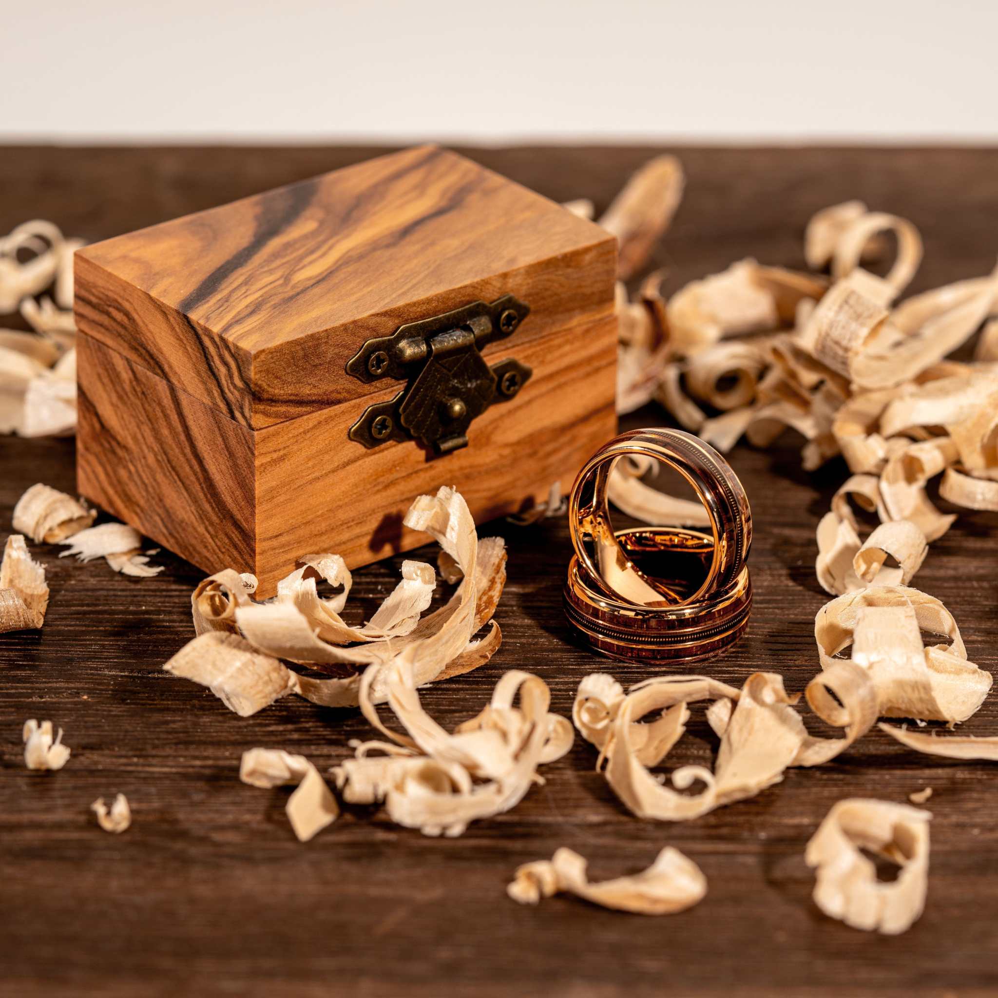 Guitar String Whiskey Barrel Ring in olive wood box with wood shavings, handcrafted tungsten and rose gold design.