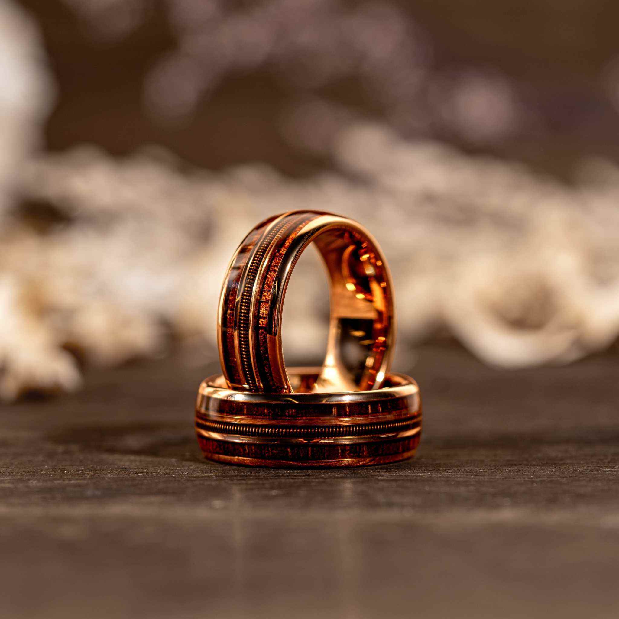 Rose gold and tungsten guitar string whiskey barrel wood ring with intricate inlay and polished finish