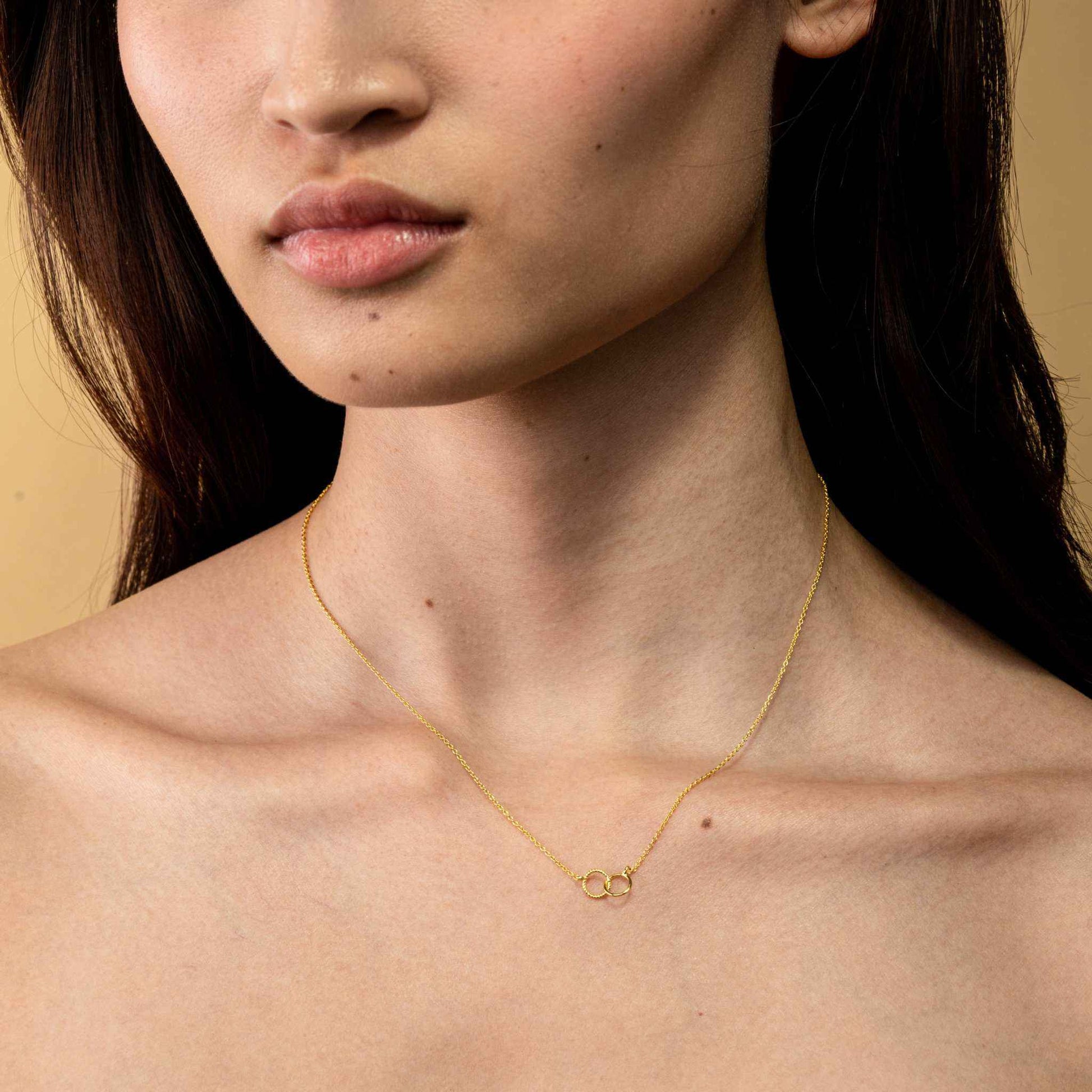 Dainty Interlocking Circle Necklace on model, crafted from recycled 925 Sterling Silver with 14k gold finish.