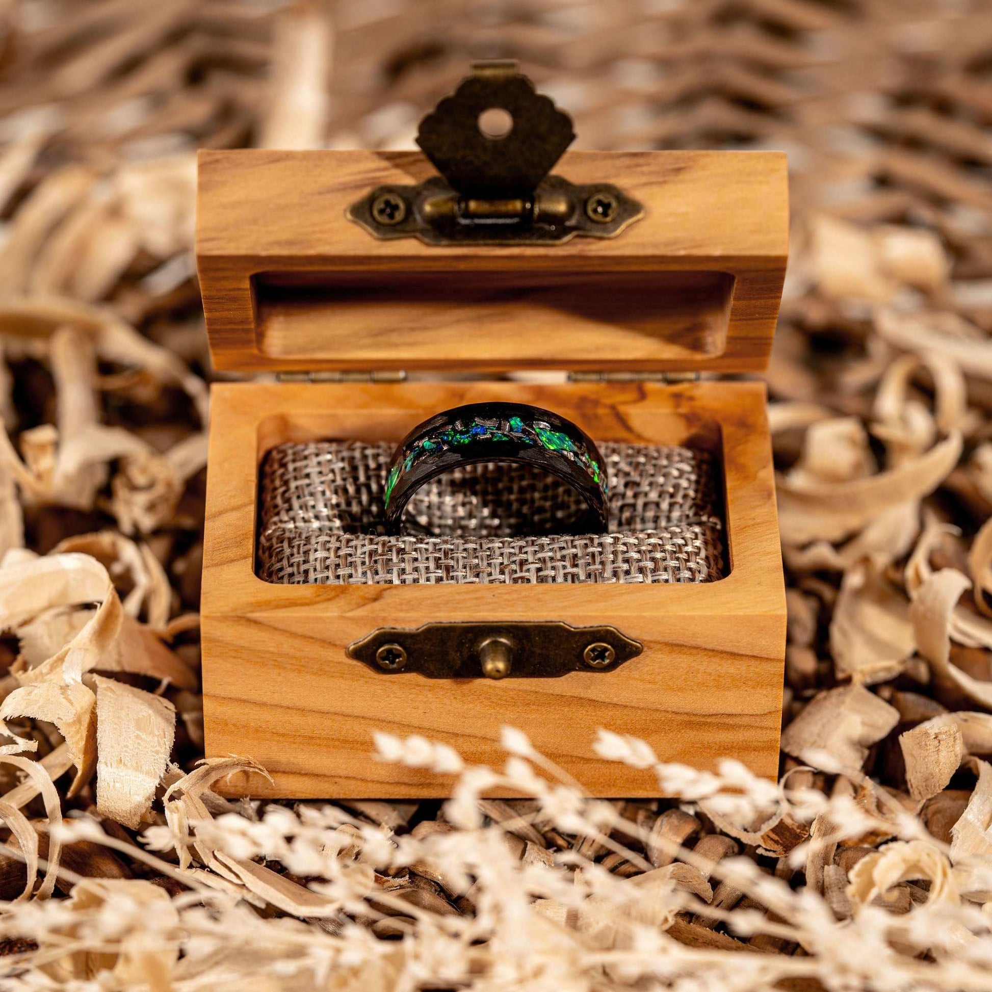 Meteorite and green opal ring in a wooden box surrounded by natural shavings.