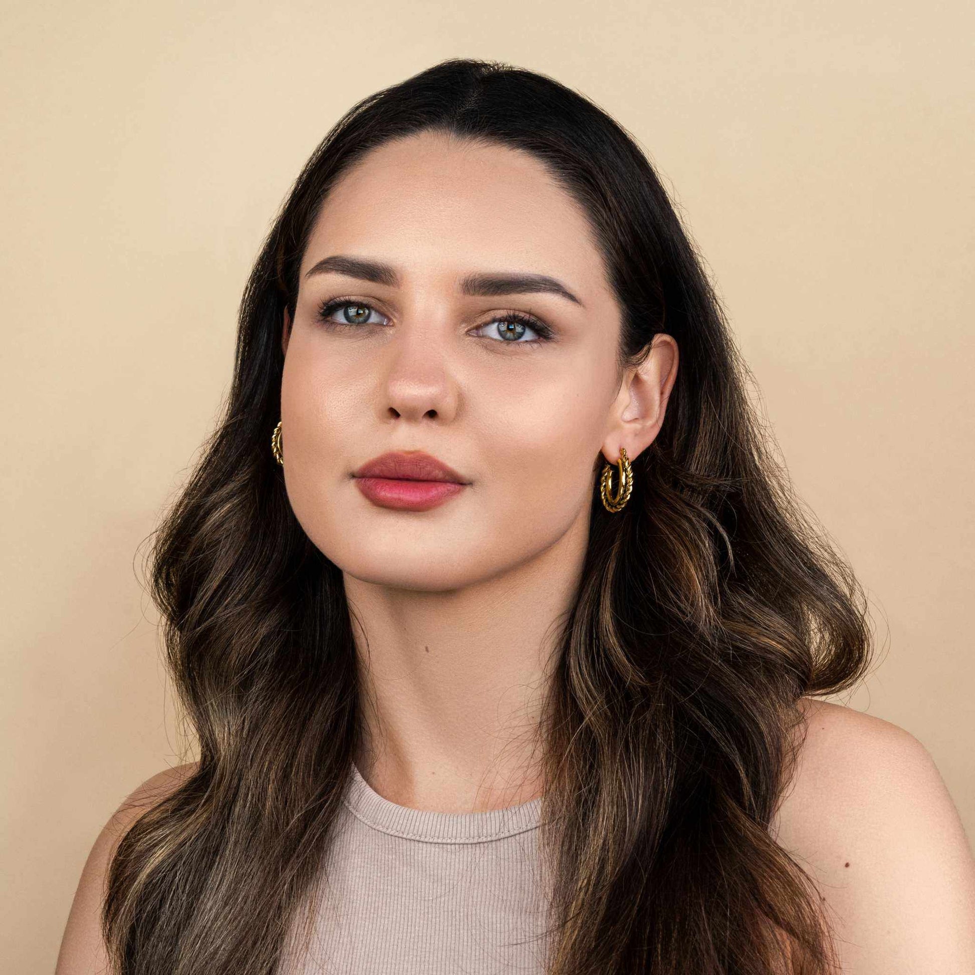 Mirage Twisted Hoop Earrings in 18k PVD gold plating worn by model.