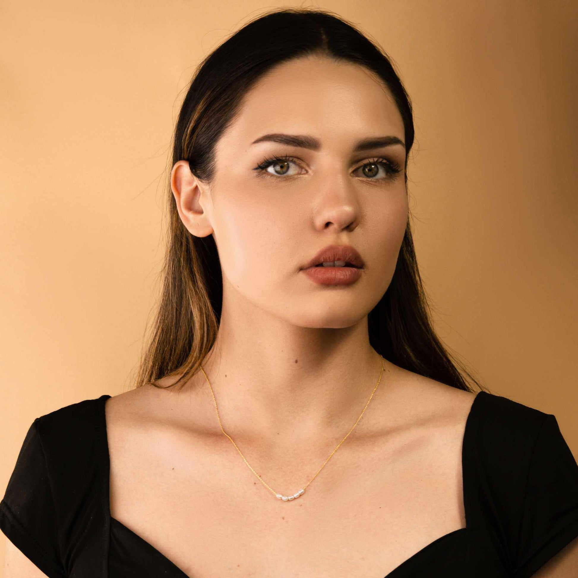 Minimalist pearl bead necklace on woman with black dress.