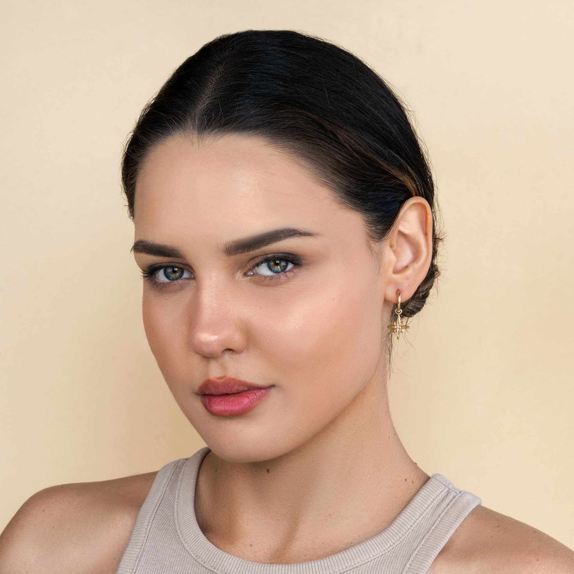 Woman wearing Starburst Huggie Earrings, 18k PVD gold plated, tarnish-free, hypoallergenic.