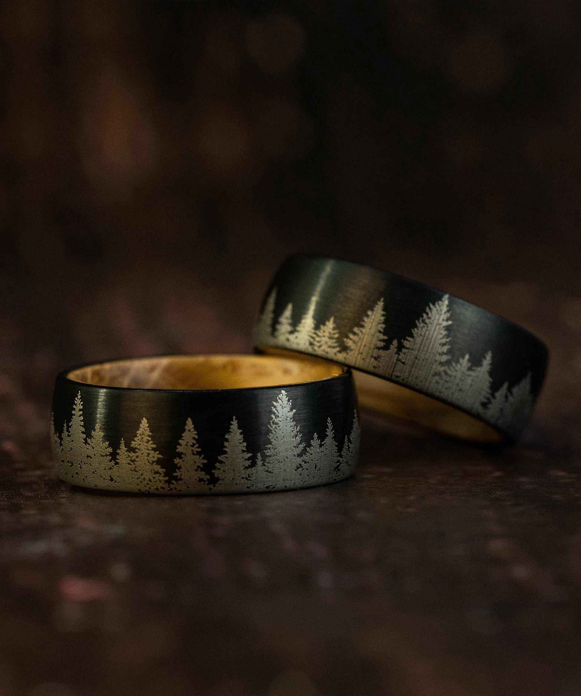 Whiskey barrel tungsten carbide ring with etched pine tree forest design and wooden inner band.